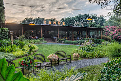 A Canopy restaurant with a garden in front.