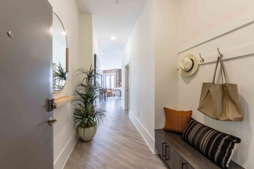 a hallway with a door to a room with bags and a plant