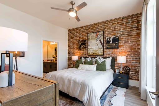 a bedroom with a bed and a brick wall