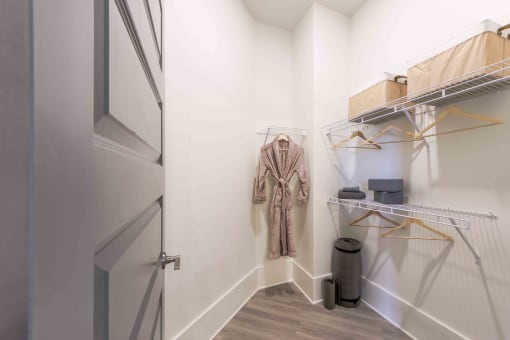 a walk in closet with a jacket hanging on the wall