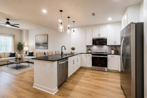 A modern kitchen with a black countertop and stainless steel appliances.