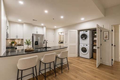 A modern kitchen with a black countertop and white cabinets.