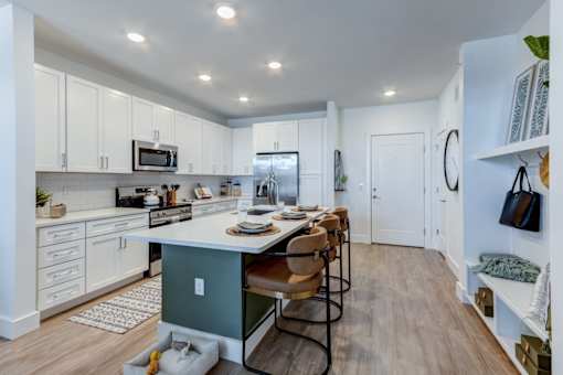 A kitchen with white cabinets and a green island.