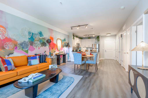 a living room with a couch a table and chairs and a kitchen in the background