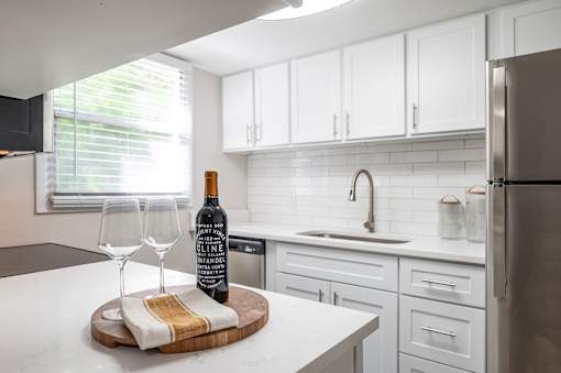 A kitchen with a wine bottle and glasses on the counter.