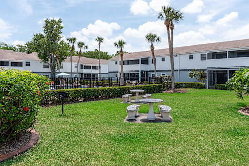 A white building with a black fence and a green lawn with a picnic table.