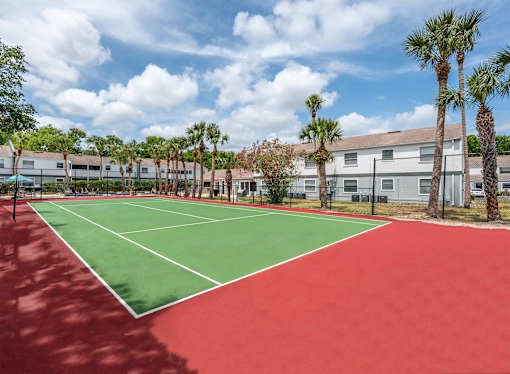 A tennis court with red and green surface and white lines.