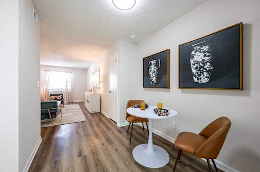 A room with a table and chairs and two pictures on the wall.
