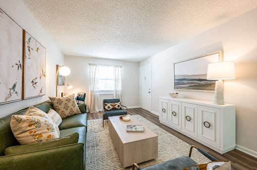 A living room with a green couch, a coffee table, and a painting on the wall.