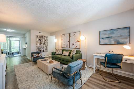 A living room with a green couch, a blue chair, and a painting on the wall.