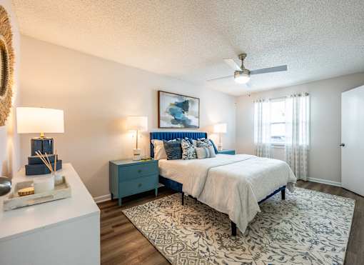 A bedroom with a bed, nightstand, and a ceiling fan.