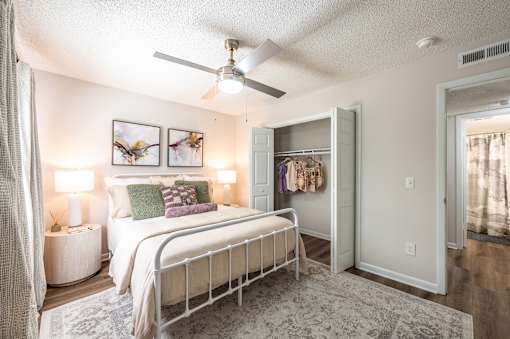 A bedroom with a bed, a ceiling fan, and a wardrobe.