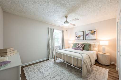 A bedroom with a bed, nightstand, and a ceiling fan.
