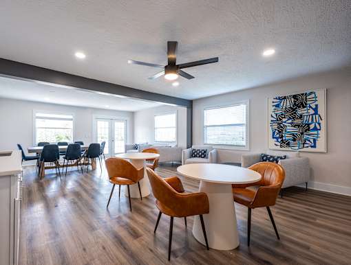 A room with a white ceiling fan and a white table with chairs.