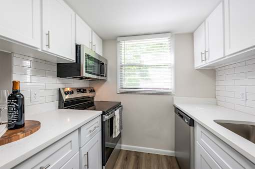 A kitchen with white cabinets and a black microwave.