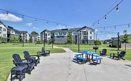 A sunny day at a park with picnic tables and chairs.