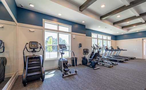 A gym with treadmills, elliptical machines, and other exercise equipment.