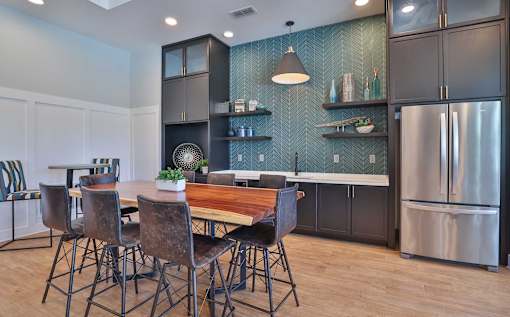 A kitchen with a table and chairs in the foreground and a refrigerator in the background.