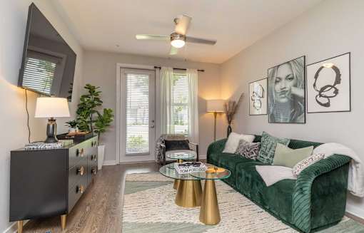 A living room with a green couch, a coffee table, and a TV on the wall.