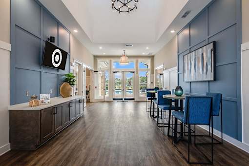 A long hallway with blue chairs and a TV mounted on the wall.