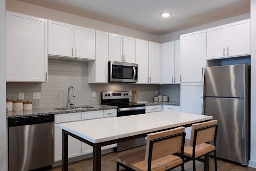 A kitchen with a table and chairs in front of a refrigerator.