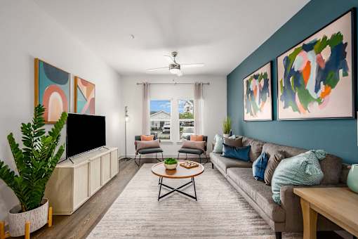 A living room with a television, couch, and two paintings on the wall.