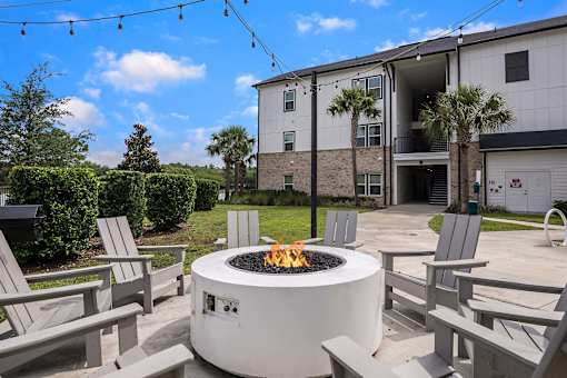 A fire pit is surrounded by chairs in a courtyard.