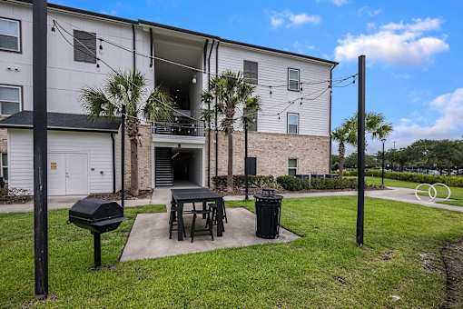A white apartment building with a black mailbox and a trash can.