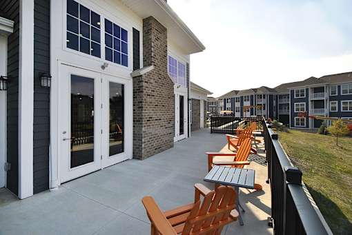 A row of wooden chairs are lined up on a concrete patio.