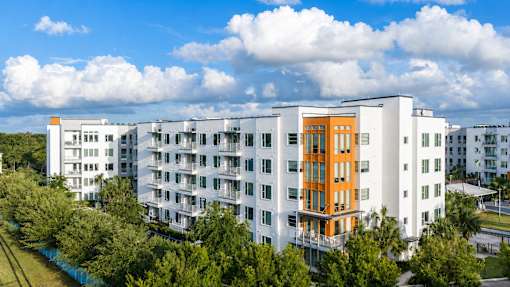 A modern apartment building with a mix of white and orange balconies.