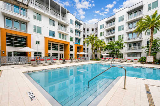 A swimming pool in front of a white and orange building.