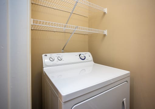 a washer and dryer in a laundry room with a rack on the wall