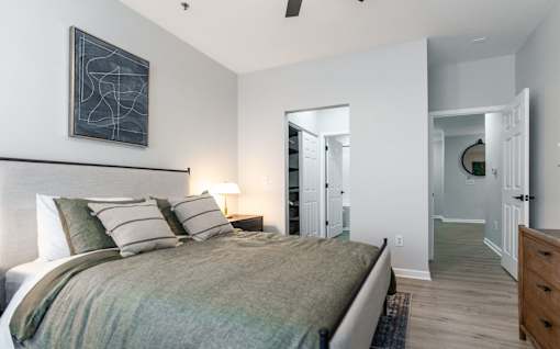 A bedroom with a bed, nightstands, and a painting on the wall.