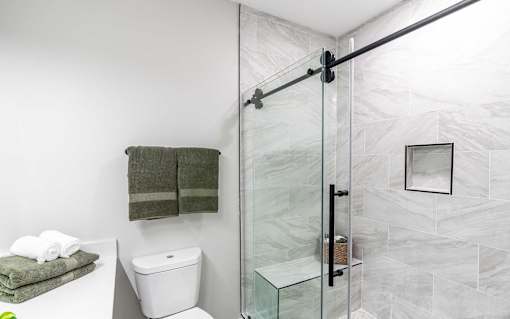 A bathroom with a toilet, a towel, and a glass shower door.
