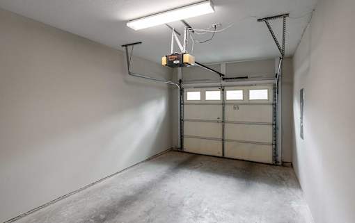 A garage with a white wall and a grey floor.