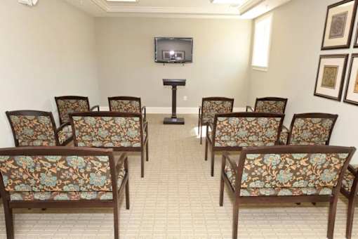 A room with a television and chairs with floral patterns.