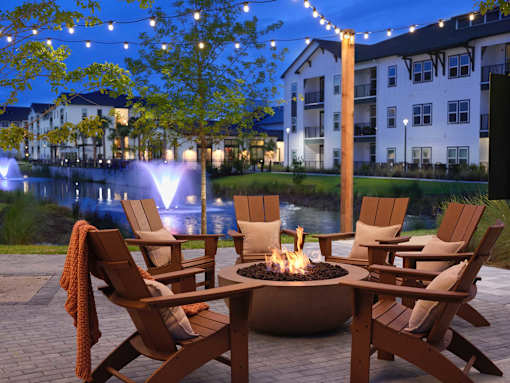 A fire pit sits in the middle of a patio surrounded by chairs.