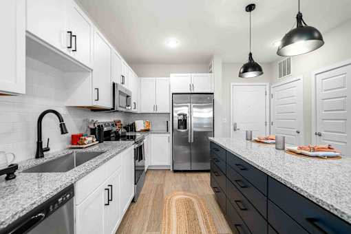 A modern kitchen with white cabinets and a wooden floor.