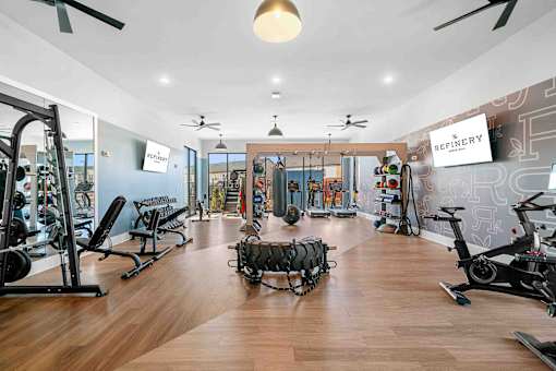 A gym with a variety of equipment including treadmills, weights, and exercise bikes.