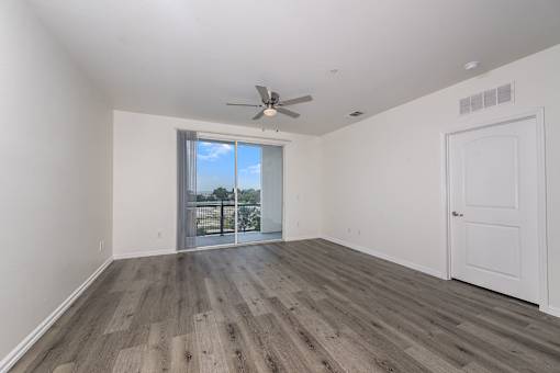 A room with a ceiling fan and sliding glass doors.