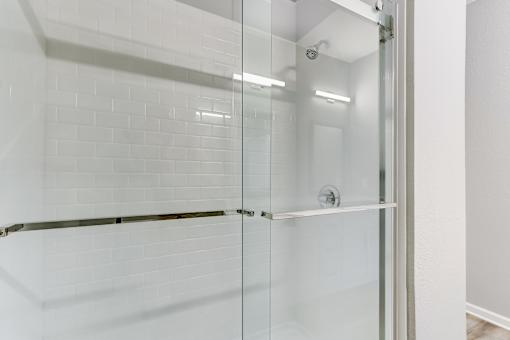 A white tiled shower with a glass door.