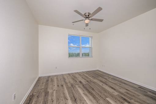 A room with a ceiling fan and a window with blinds.