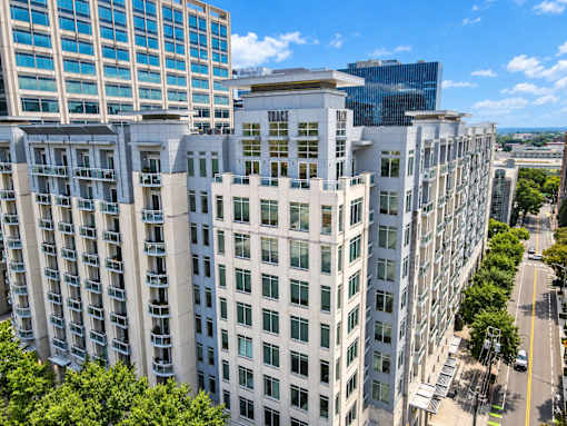 A tall white building with many windows is in the foreground of a city street.