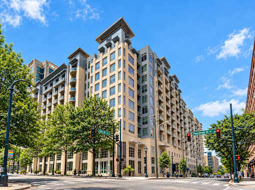 A large, modern building with many windows is situated on a street corner.