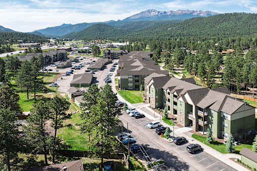 A large apartment complex with a parking lot in front of it.