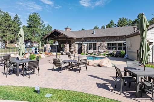 A patio with a table and chairs and umbrellas.