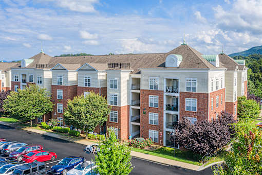 A large apartment complex with a parking lot in front.