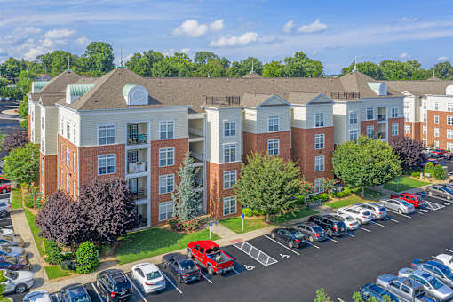 A large apartment complex with a parking lot in front.