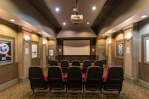 A movie theater with red seats and a screen.
