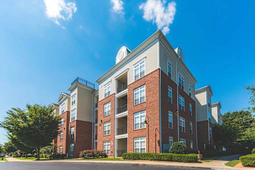 A large red brick apartment building with a white roof and a balcony on the second floor.